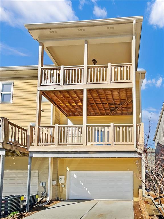 view of front facade with a balcony, an attached garage, central AC unit, and driveway