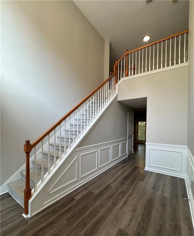 1415 Stoney Field Pl, Lawrenceville, GA 30043 - stairs with wood finished floors, a towering ceiling, a decorative wall, a wainscoted wall, and recessed lighting