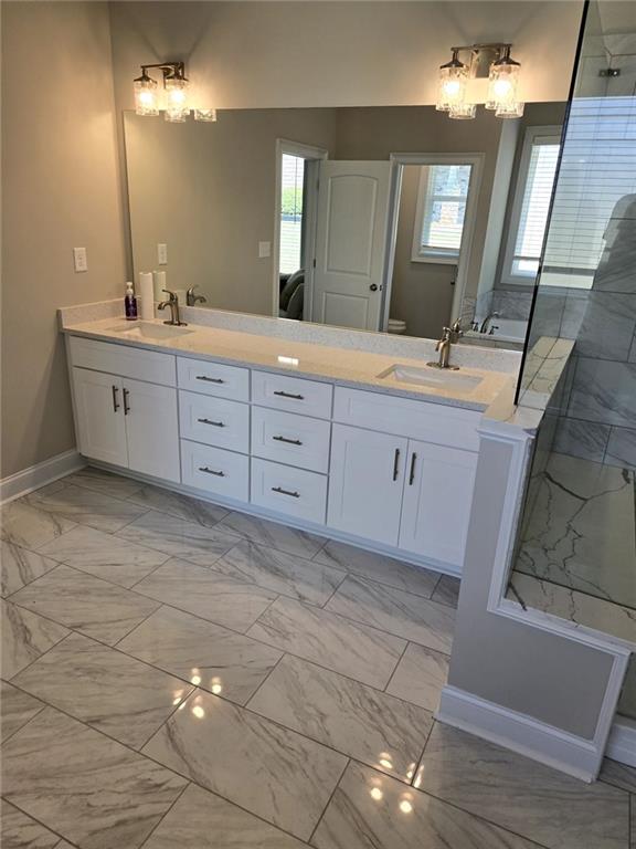 7260 Bluewater Ln, Douglasville, GA 30135 - bathroom featuring a sink, double vanity, a stall shower, baseboards, and marble finish floor
