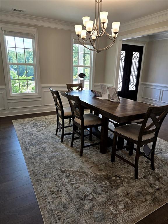 7260 Bluewater Ln, Douglasville, GA 30135 - dining space featuring dark wood-style flooring, visible vents, a chandelier, a decorative wall, and ornamental molding