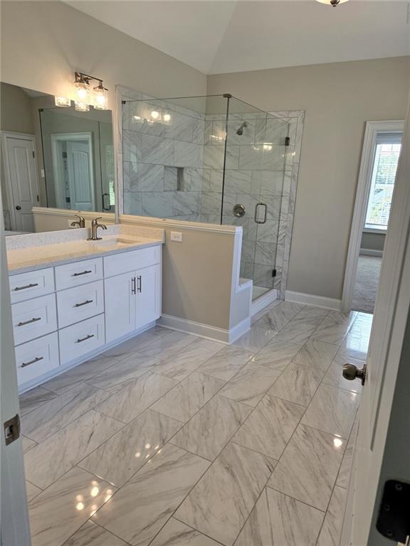 7260 Bluewater Ln, Douglasville, GA 30135 - bathroom with baseboards, lofted ceiling, marble finish floor, a shower stall, and vanity