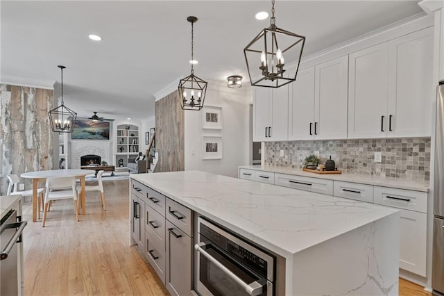 4030 Scenic View Ct, Cumming, GA 30028 - kitchen with a chandelier, a kitchen island, open floor plan, light wood finished floors, and a fireplace