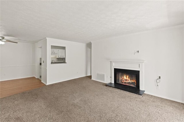 unfurnished living room with ceiling fan, carpet, and a textured ceiling