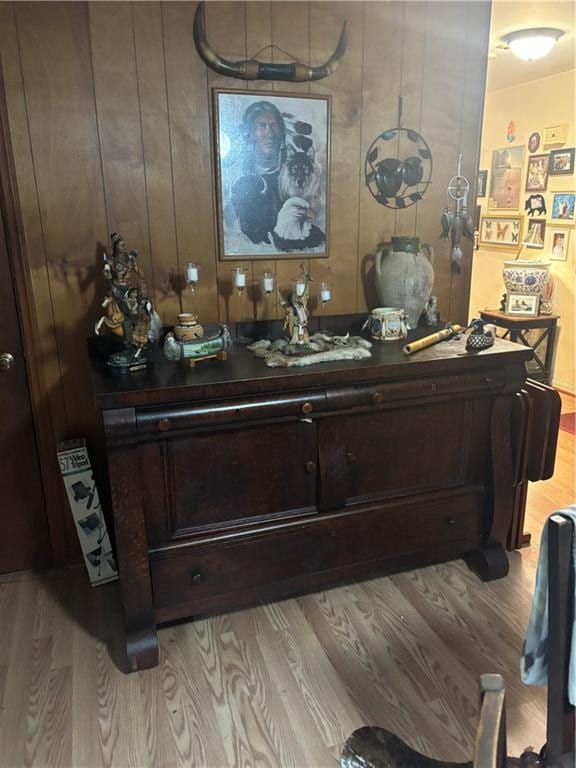 bar with light wood-type flooring, dark brown cabinetry, and wooden walls