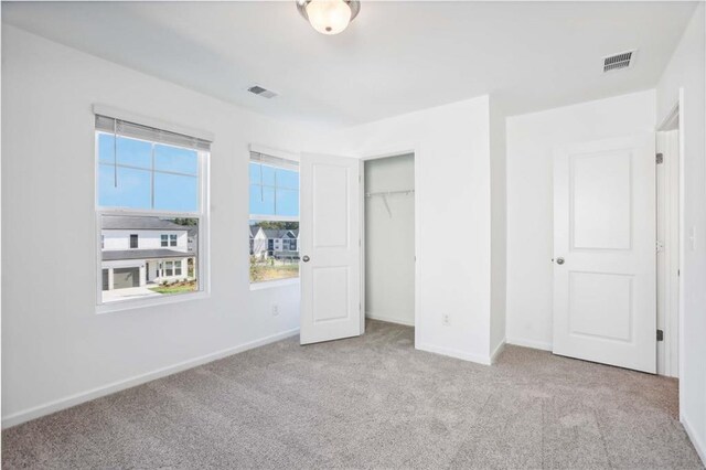 unfurnished bedroom featuring a closet and light colored carpet