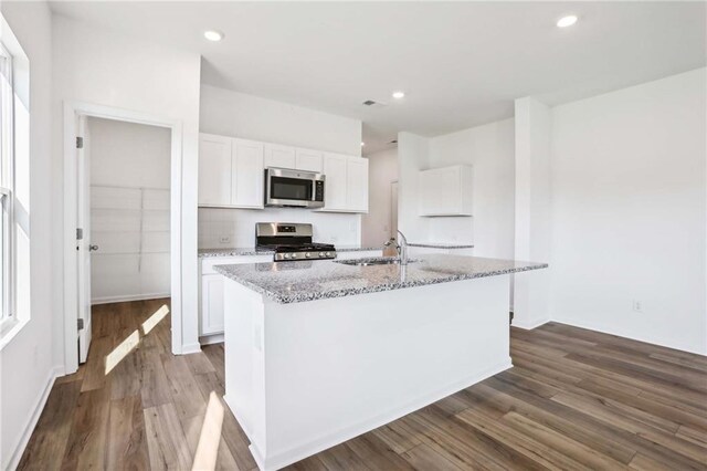 kitchen featuring a center island with sink, appliances with stainless steel finishes, dark hardwood / wood-style floors, and white cabinetry