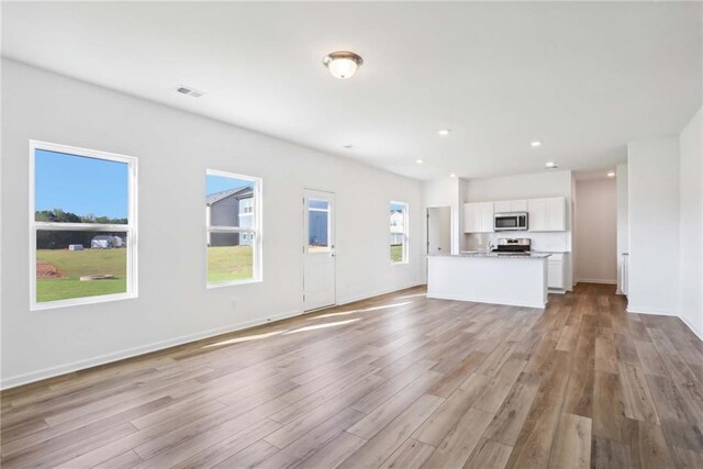 unfurnished living room with light hardwood / wood-style flooring and a healthy amount of sunlight