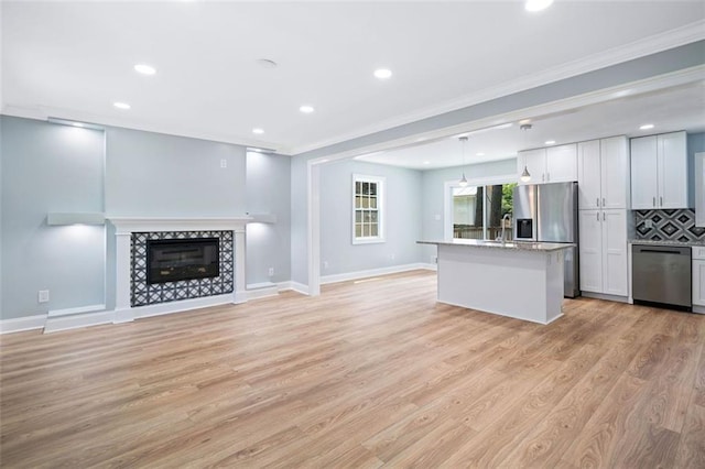 3050 Woodland Dr NW, Kennesaw, GA 30152 - kitchen featuring appliances with stainless steel finishes, ornamental molding, open floor plan, recessed lighting, and a tile fireplace