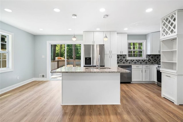 3050 Woodland Dr NW, Kennesaw, GA 30152 - kitchen with appliances with stainless steel finishes, a sink, a kitchen island with sink, light stone countertops, and backsplash