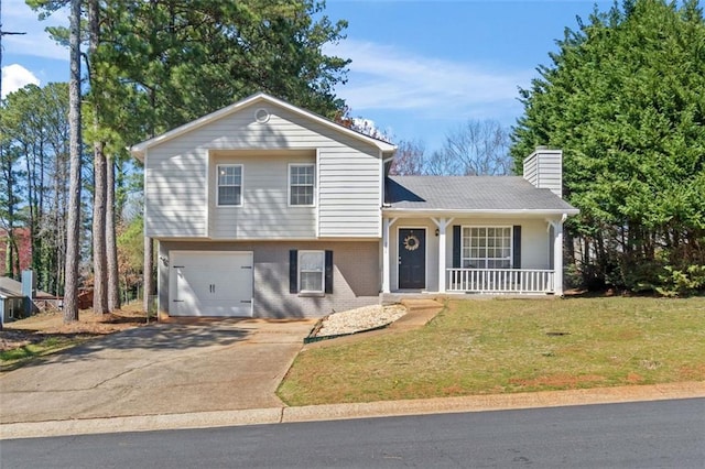 tri-level home featuring covered porch, a chimney, a front lawn, concrete driveway, and brick siding