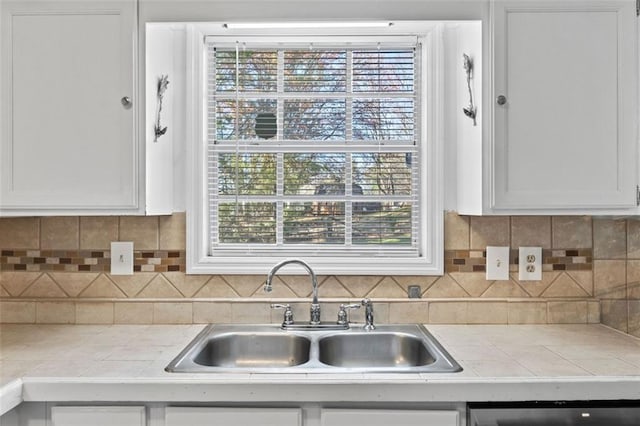 kitchen featuring dishwashing machine, tile countertops, white cabinets, and a sink