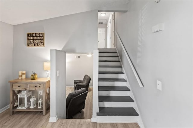 stairs with visible vents, baseboards, and wood finished floors