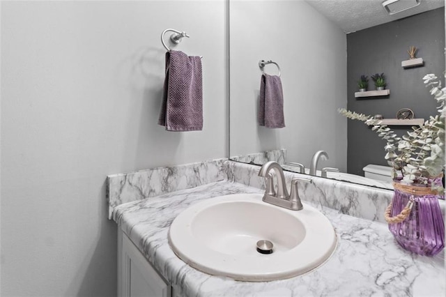 bathroom featuring vanity, toilet, and a textured ceiling