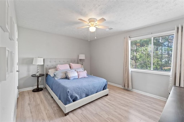 bedroom featuring light wood-style floors, baseboards, and a textured ceiling