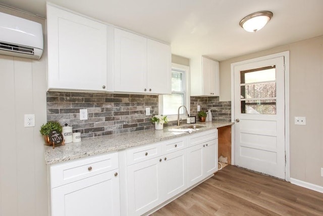 272 Old Sudie Rd, Hiram, GA 30141 - kitchen with a wall mounted AC, a sink, tasteful backsplash, light wood finished floors, and white cabinets