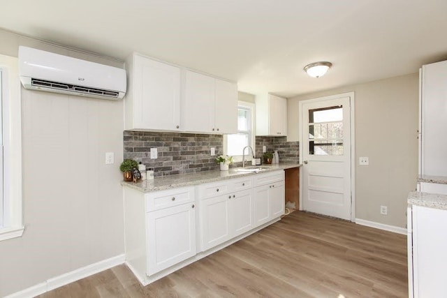 272 Old Sudie Rd, Hiram, GA 30141 - kitchen featuring an AC wall unit, a sink, baseboards, white cabinetry, and tasteful backsplash