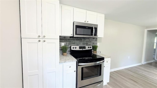 272 Old Sudie Rd, Hiram, GA 30141 - kitchen with stainless steel appliances, light stone countertops, white cabinetry, backsplash, and light wood-style flooring