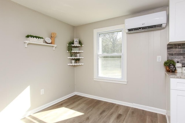 272 Old Sudie Rd, Hiram, GA 30141 - unfurnished dining area with a wall mounted air conditioner, wood finished floors, and baseboards