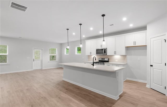 kitchen featuring visible vents, decorative backsplash, light countertops, white cabinetry, and appliances with stainless steel finishes