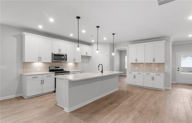 kitchen featuring appliances with stainless steel finishes, a sink, light wood-style floors, light countertops, and decorative backsplash