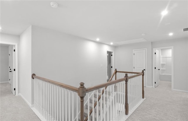 hallway with carpet floors, recessed lighting, baseboards, and an upstairs landing