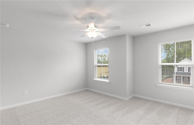spare room with visible vents, a ceiling fan, baseboards, and light colored carpet