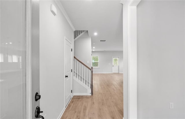 corridor featuring baseboards, recessed lighting, light wood finished floors, and stairs