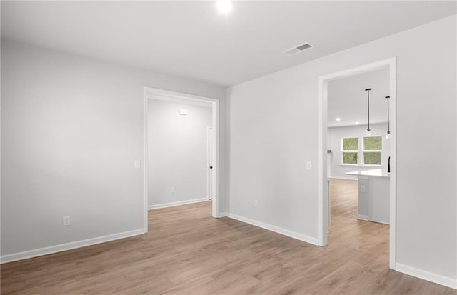unfurnished room featuring baseboards, visible vents, and light wood finished floors