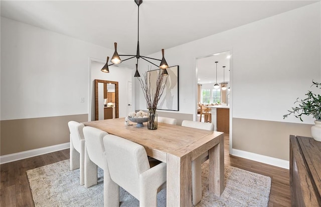 dining space featuring baseboards, wood finished floors, and a chandelier