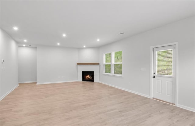 unfurnished living room featuring recessed lighting, light wood finished floors, and a wealth of natural light