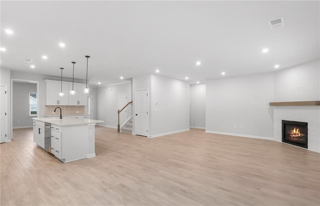 kitchen with recessed lighting, light countertops, dishwasher, and a center island with sink