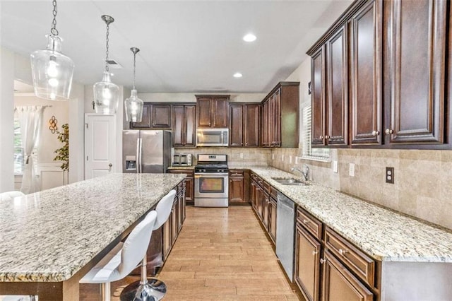 kitchen featuring decorative backsplash, light wood-style flooring, a sink, and stainless steel appliances