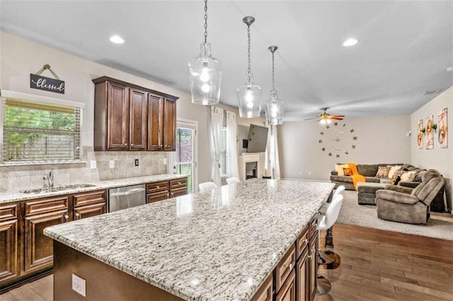 kitchen featuring a ceiling fan, a sink, open floor plan, light wood-style floors, and dishwasher