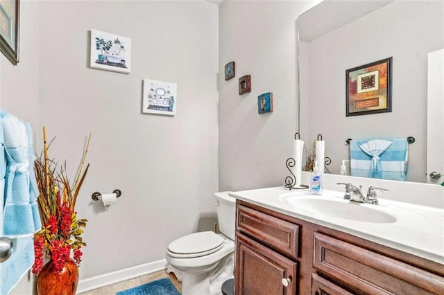 half bath featuring toilet, vanity, and baseboards