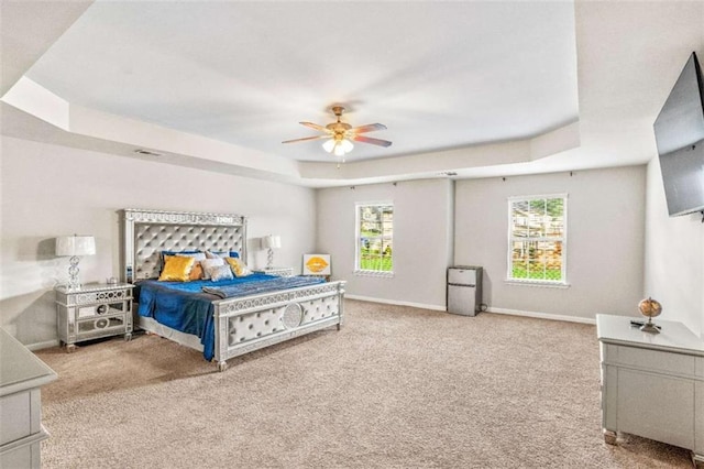 bedroom featuring a raised ceiling, multiple windows, carpet flooring, and baseboards