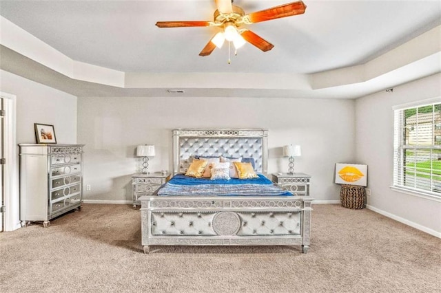 bedroom featuring ceiling fan, a raised ceiling, baseboards, and carpet floors