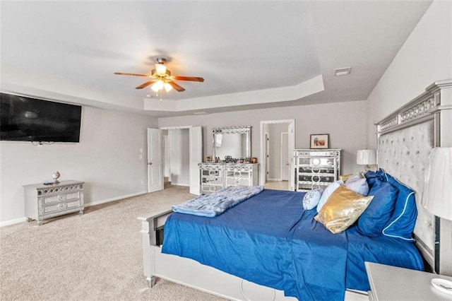 carpeted bedroom featuring a ceiling fan, a raised ceiling, and baseboards