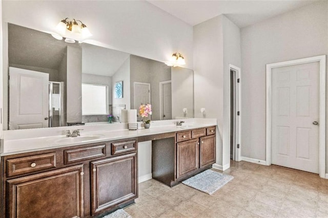 bathroom with a sink, baseboards, lofted ceiling, and double vanity