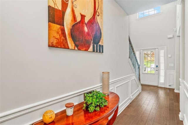 foyer featuring a wealth of natural light, a wainscoted wall, wood finished floors, and stairs