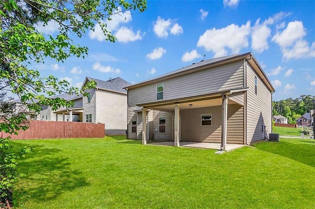 rear view of property featuring a patio area, a yard, and fence