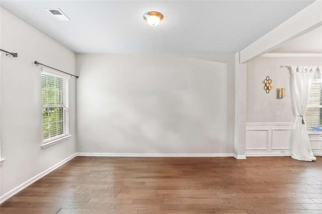 unfurnished room featuring wood finished floors, visible vents, and baseboards