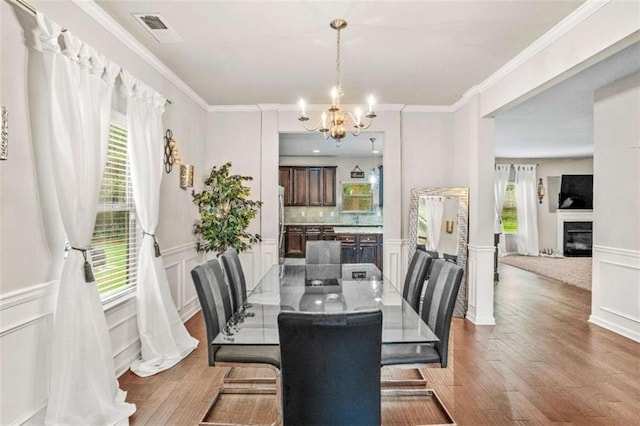 dining space featuring visible vents, a healthy amount of sunlight, ornamental molding, and an inviting chandelier