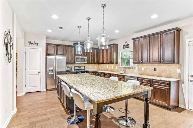 kitchen featuring dark brown cabinetry, visible vents, appliances with stainless steel finishes, and decorative backsplash