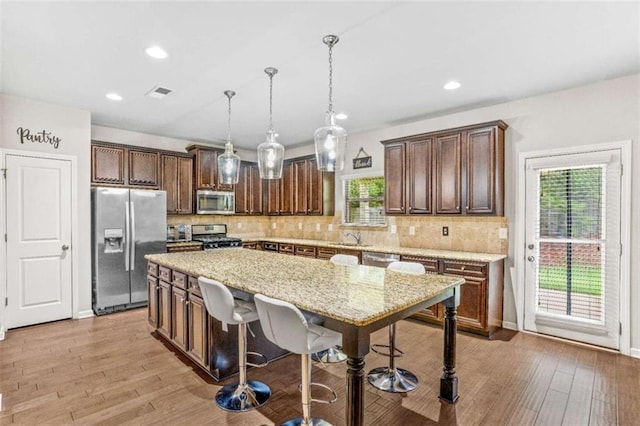 kitchen featuring light wood-style flooring, tasteful backsplash, visible vents, and appliances with stainless steel finishes