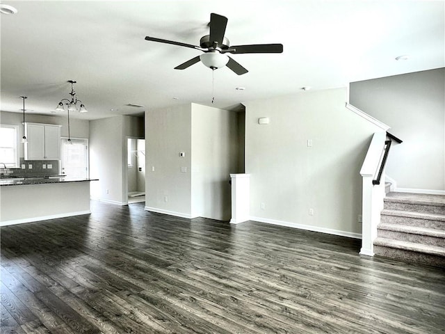 3658 Hidden Valley Cir, Lawrenceville, GA 30044 - unfurnished living room with baseboards, dark wood-style flooring, stairs, and ceiling fan with notable chandelier