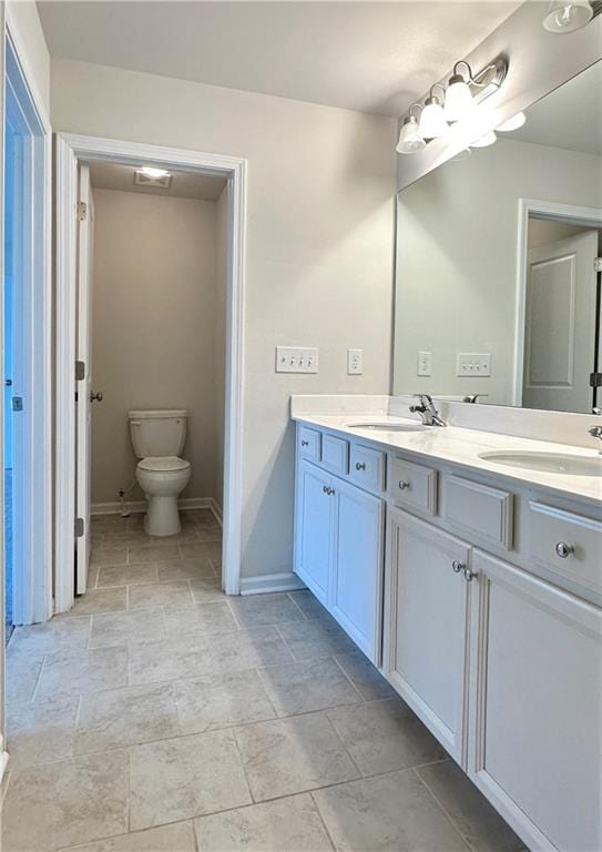 3658 Hidden Valley Cir, Lawrenceville, GA 30044 - full bath featuring double vanity, toilet, a sink, stone finish flooring, and baseboards