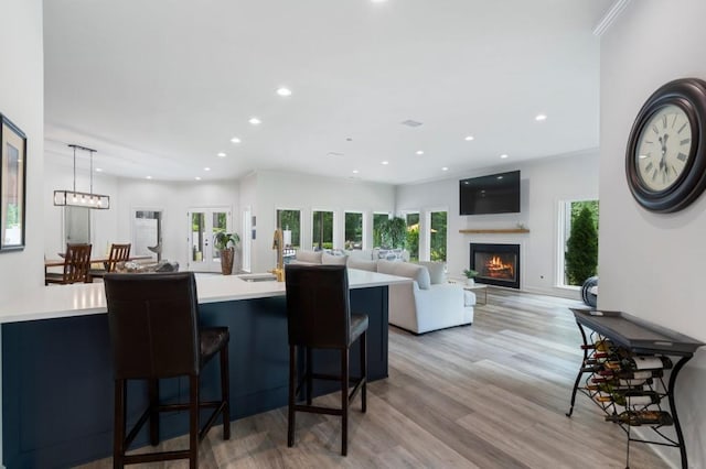 330 Longvue Ct, Johns Creek, GA 30097 - kitchen with recessed lighting, light countertops, light wood-type flooring, a lit fireplace, and a breakfast bar