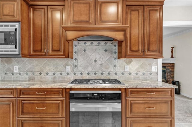 1819 Yorkshire Dr, Woodstock, GA 30189 - kitchen featuring backsplash, brown cabinetry, light stone counters, and appliances with stainless steel finishes