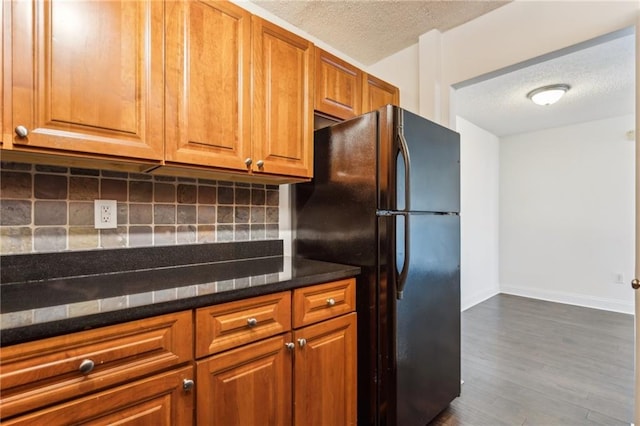 2479 Peachtree Rd NE Unit 1703, Atlanta, GA 30305 - kitchen with freestanding refrigerator, a textured ceiling, backsplash, dark wood-type flooring, and brown cabinets