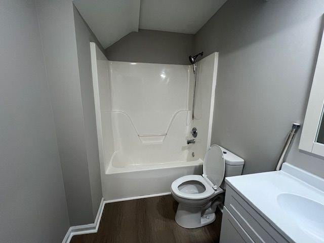 bathroom with lofted ceiling, wood finished floors, toilet, shower / washtub combination, and vanity